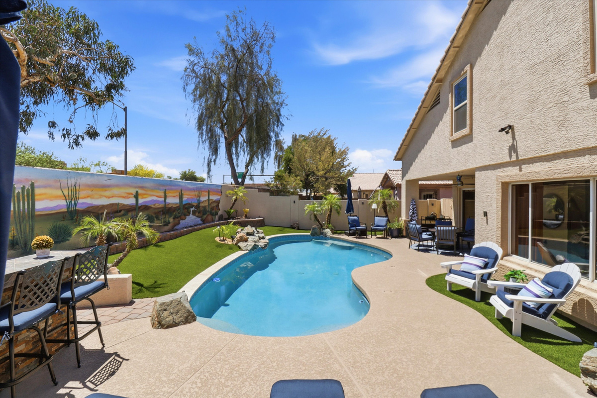 Private backyard pool with lounge seating, desert mural, mountain views, and open space for sunny outdoor relaxation.