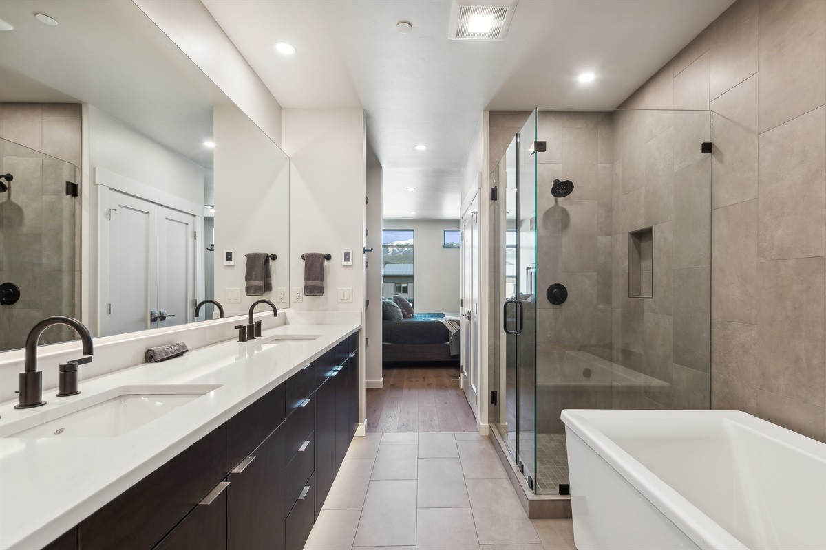 The master suite bathroom with double vanity, giant soaker tub, private toilet, and a tile shower.