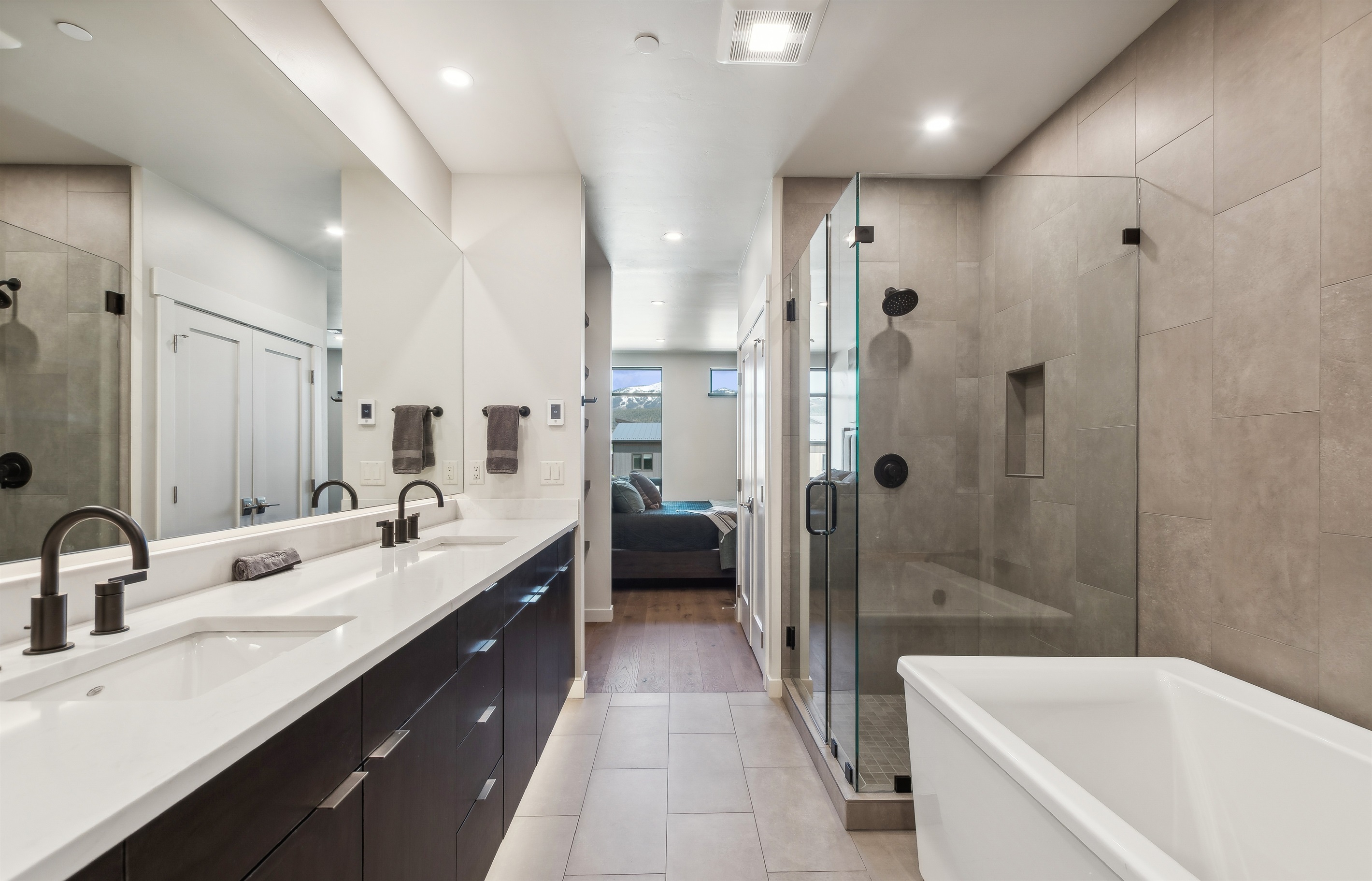 The master suite bathroom with double vanity, giant soaker tub, private toilet, and a tile shower.