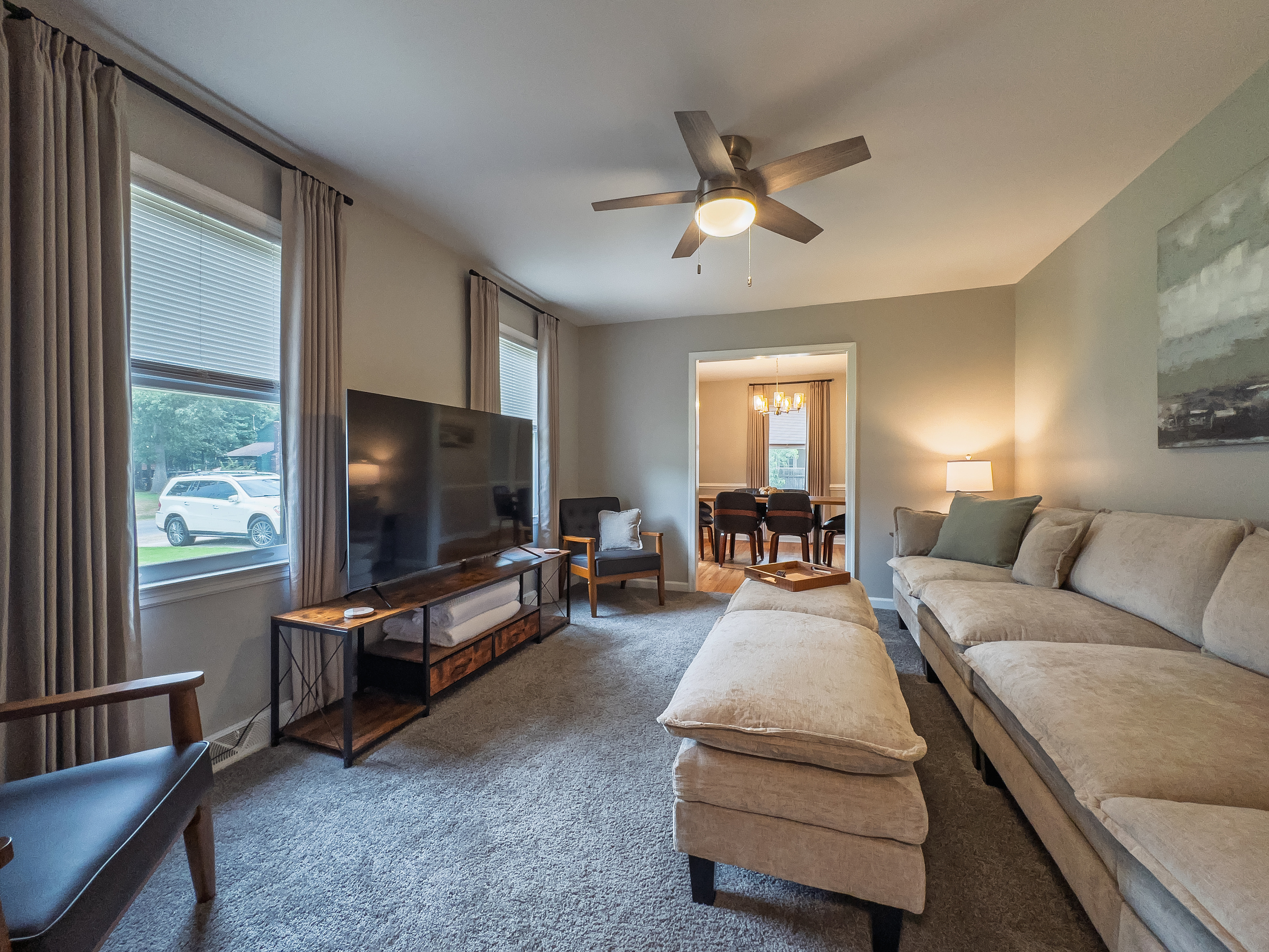Living room, 65" Smart TV, seating for 8, ceiling fan, side tables with multiple charging ports, multi light function lamps, blackout curtains.