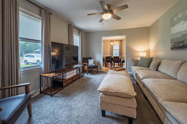 Living room, 65" Smart TV, seating for 8, ceiling fan, side tables with multiple charging ports, multi light function lamps, blackout curtains.