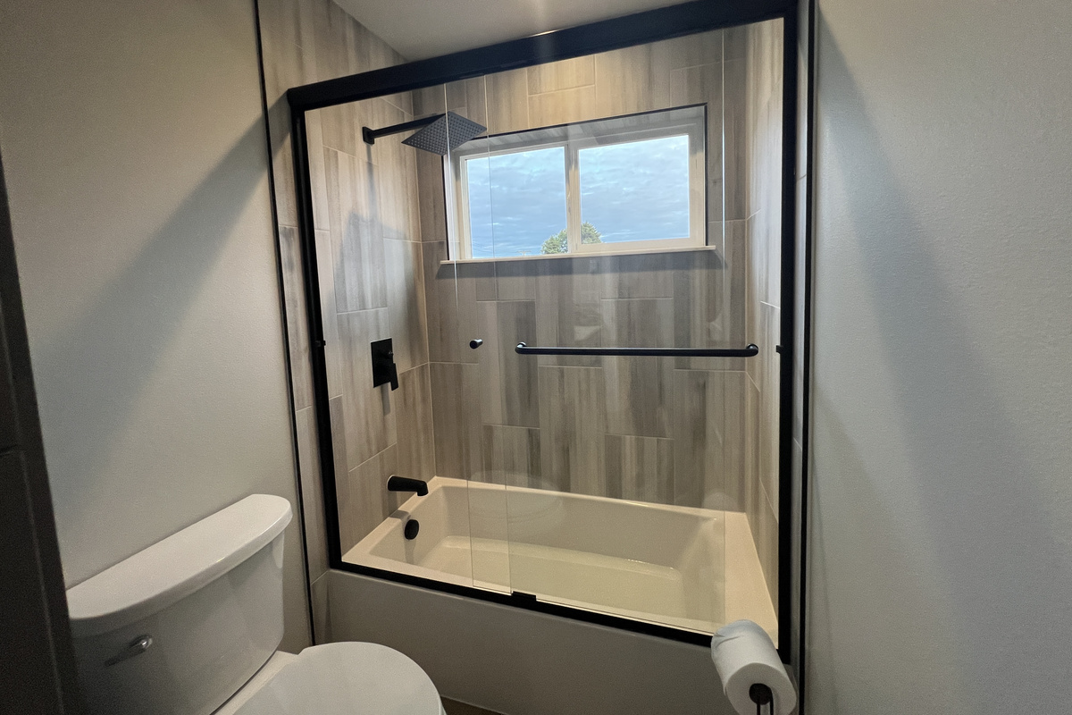 A bright, tiled bathroom with a tub-and-shower and a sunny window — rinse off the sand and relax.