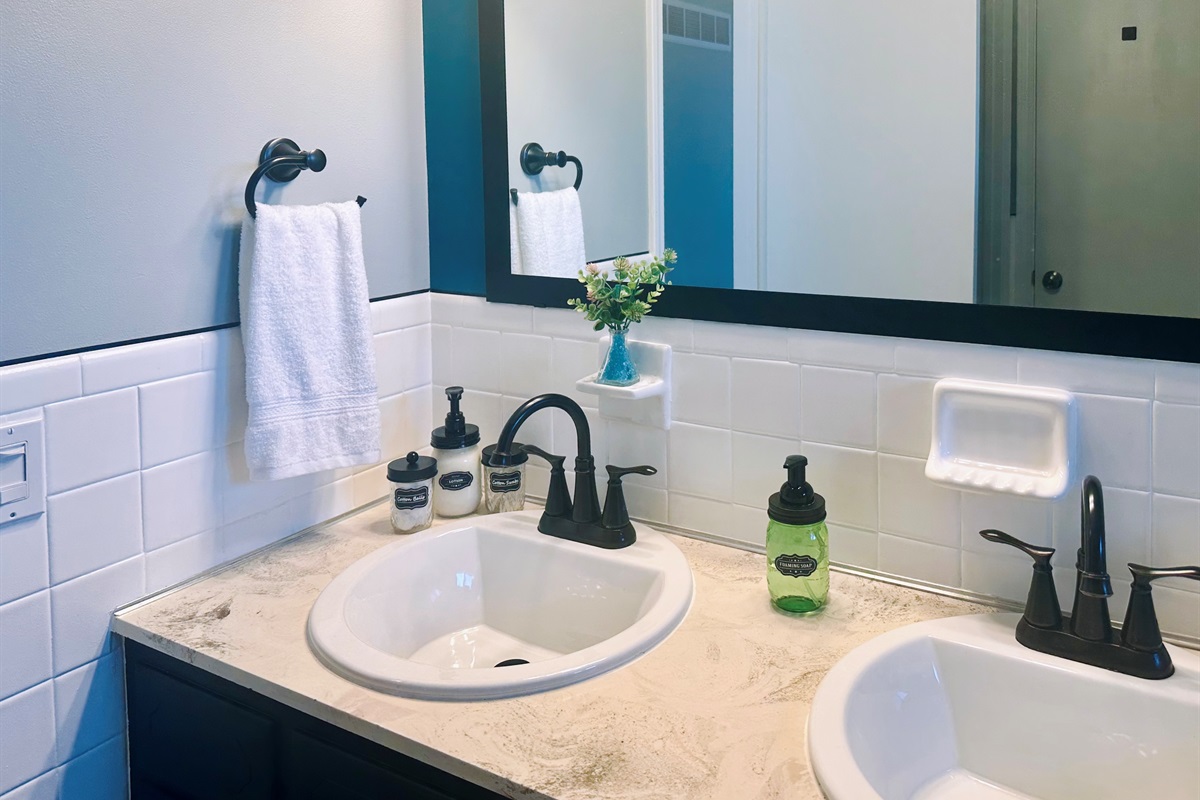 Main bathroom countertop set up with guest-ready amenities, including hand soap, lotions, and containers with cotton swabs and cotton balls. A hotel-style touch that adds comfort and convenience for longer stays.