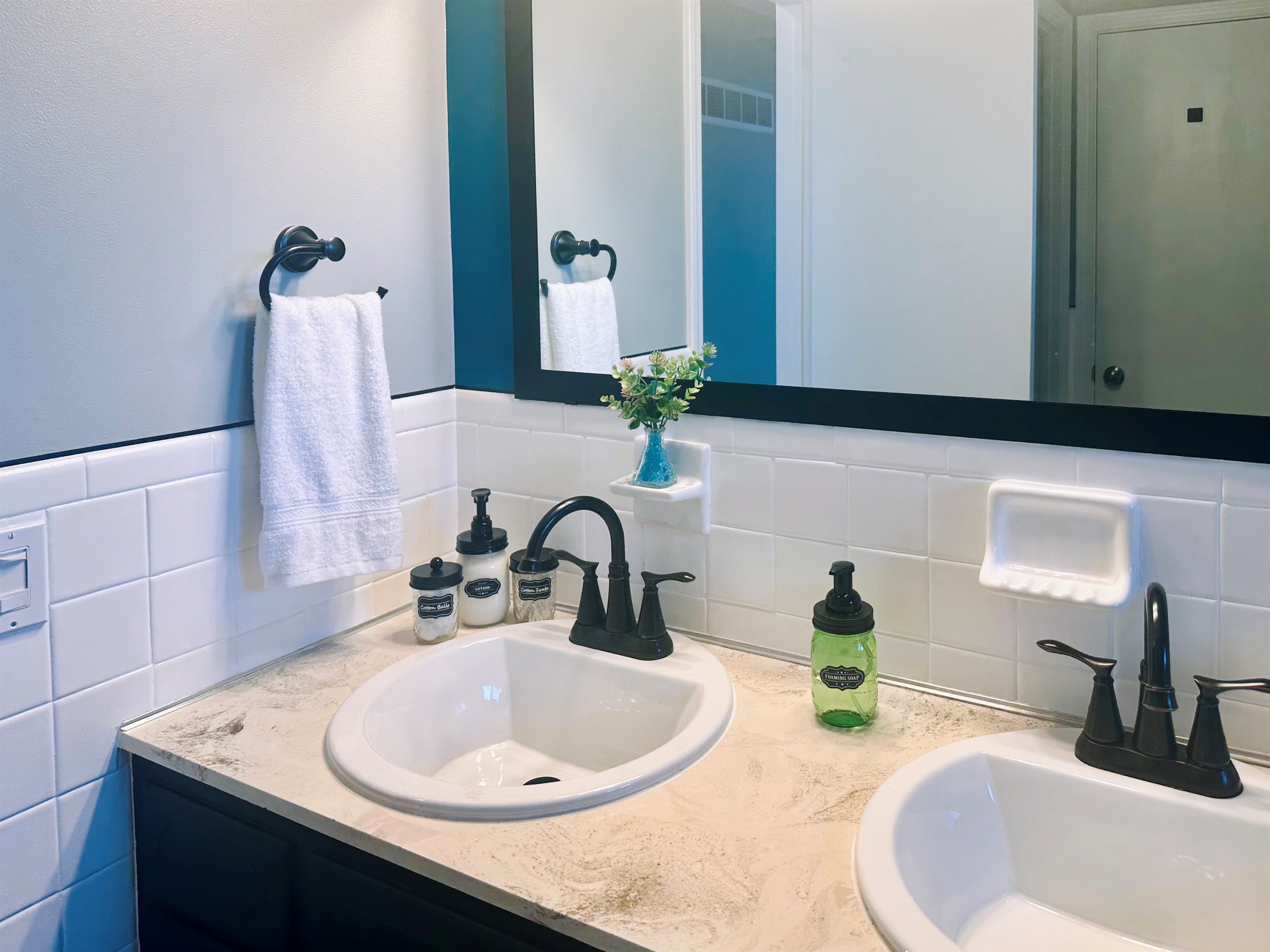 Main bathroom countertop set up with guest-ready amenities, including hand soap, lotions, and containers with cotton swabs and cotton balls. A hotel-style touch that adds comfort and convenience for longer stays.
