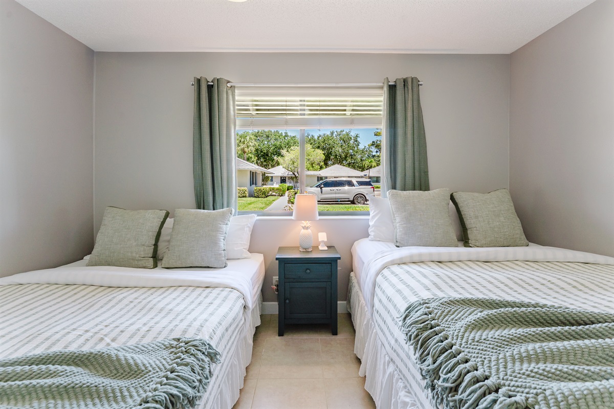 Bright guest bedroom with two queen beds, Smart TV with cable, and ample closet and dresser storage
