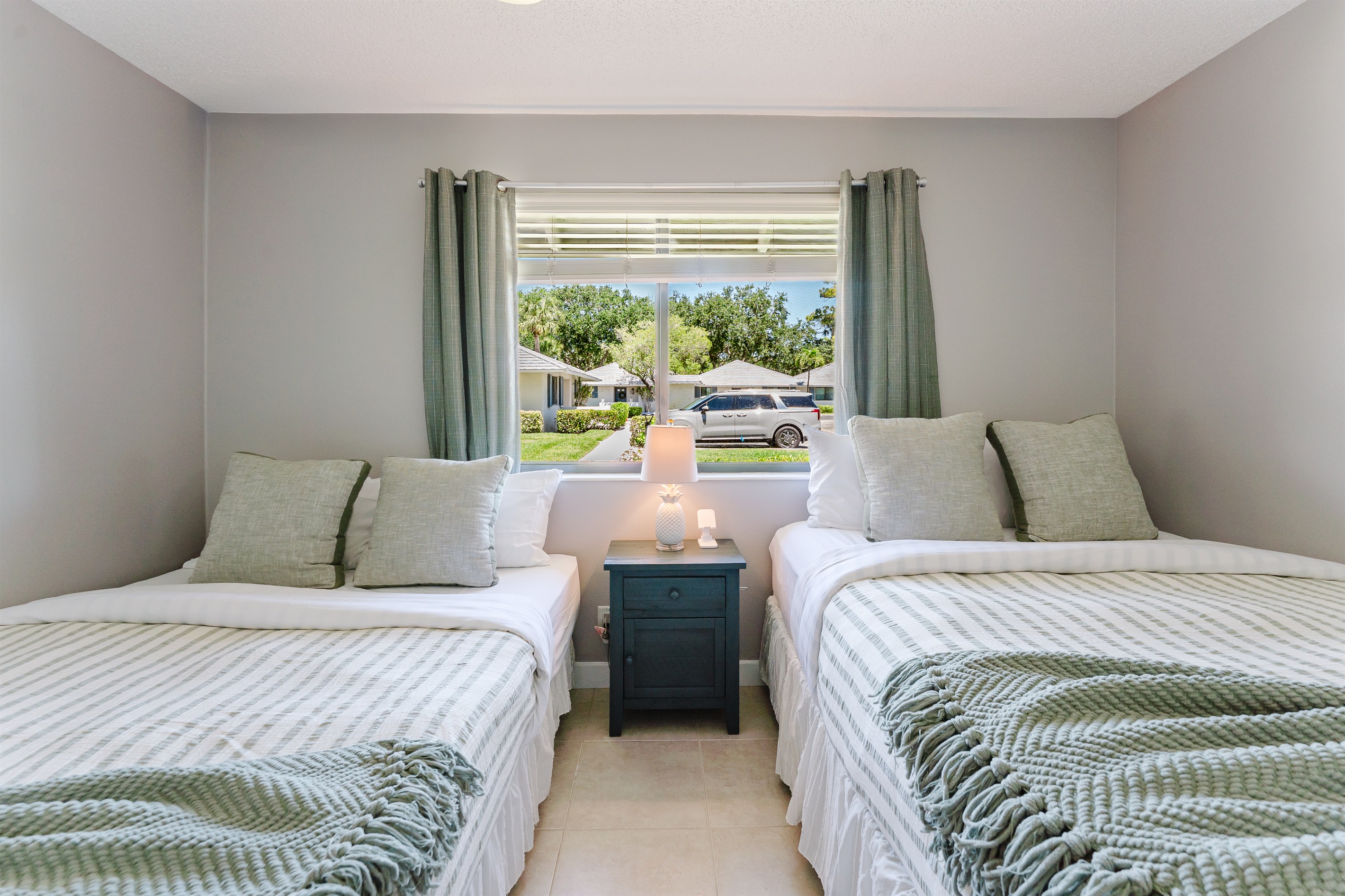 Bright guest bedroom with two queen beds, Smart TV with cable, and ample closet and dresser storage
