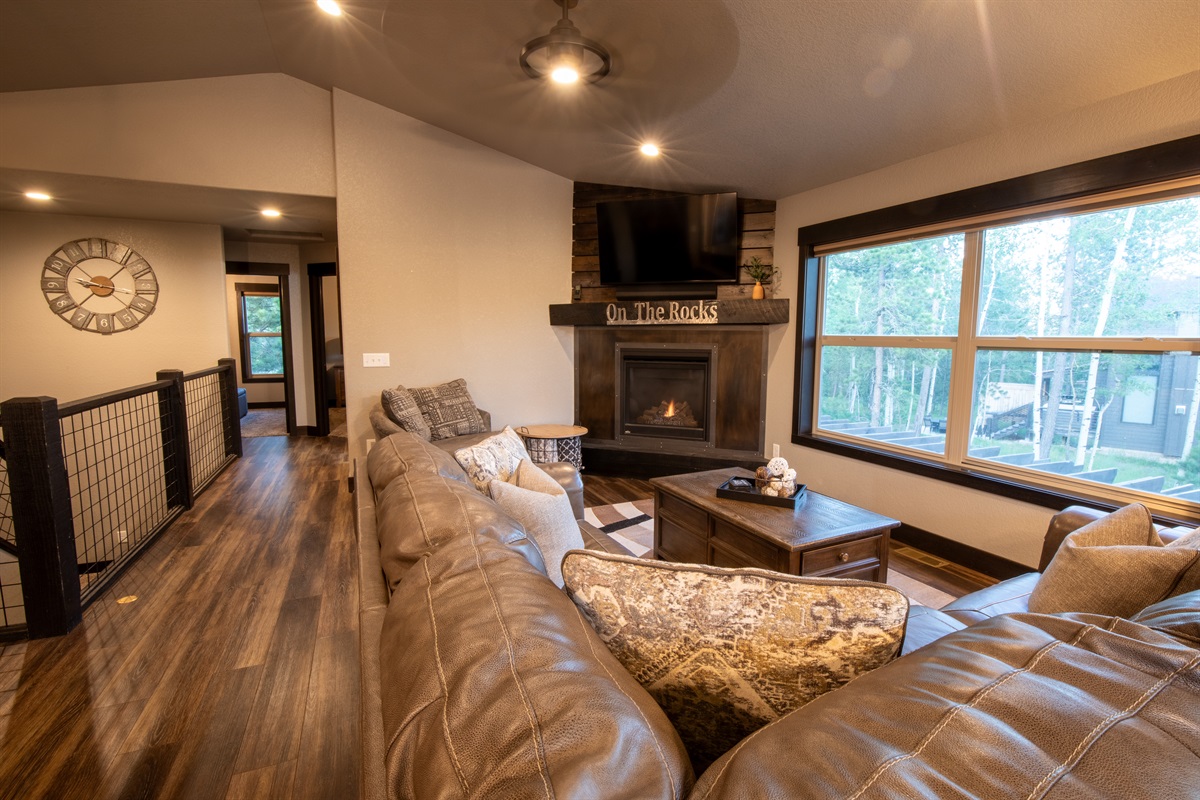Picture yourself settling into the cozy living area at "On The Rocks," sinking into the plush leather sofa as the fireplace casts a warm glow. Envision enjoying a movie on the mounted TV, with sunlight streaming through large windows.