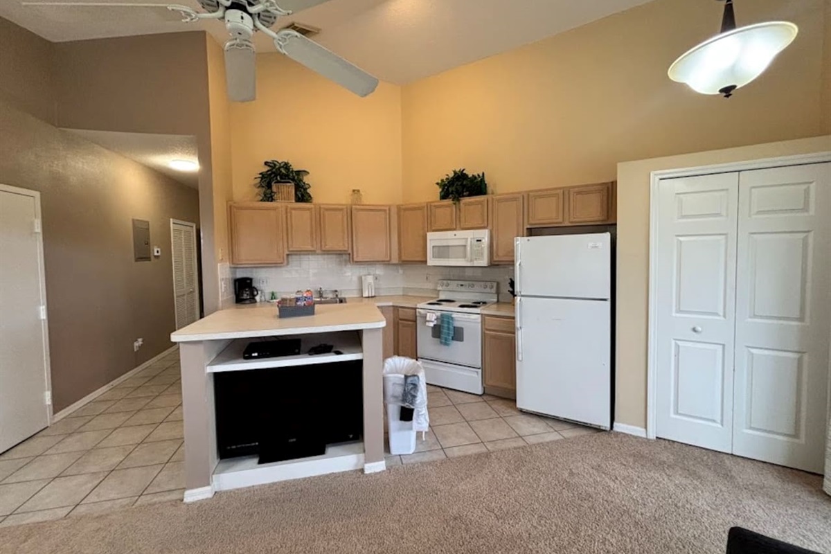 Open kitchen area with breakfast bar seating, full-size appliances, tile flooring, and easy access to the dining and living areas.