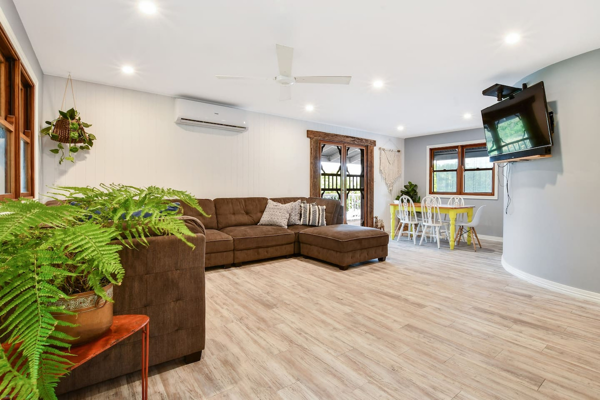 This living area at Aaron's Beachside Boat House includes a large sectional sofa, wall-mounted TV, ceiling fan and a compact dining space within the same room.