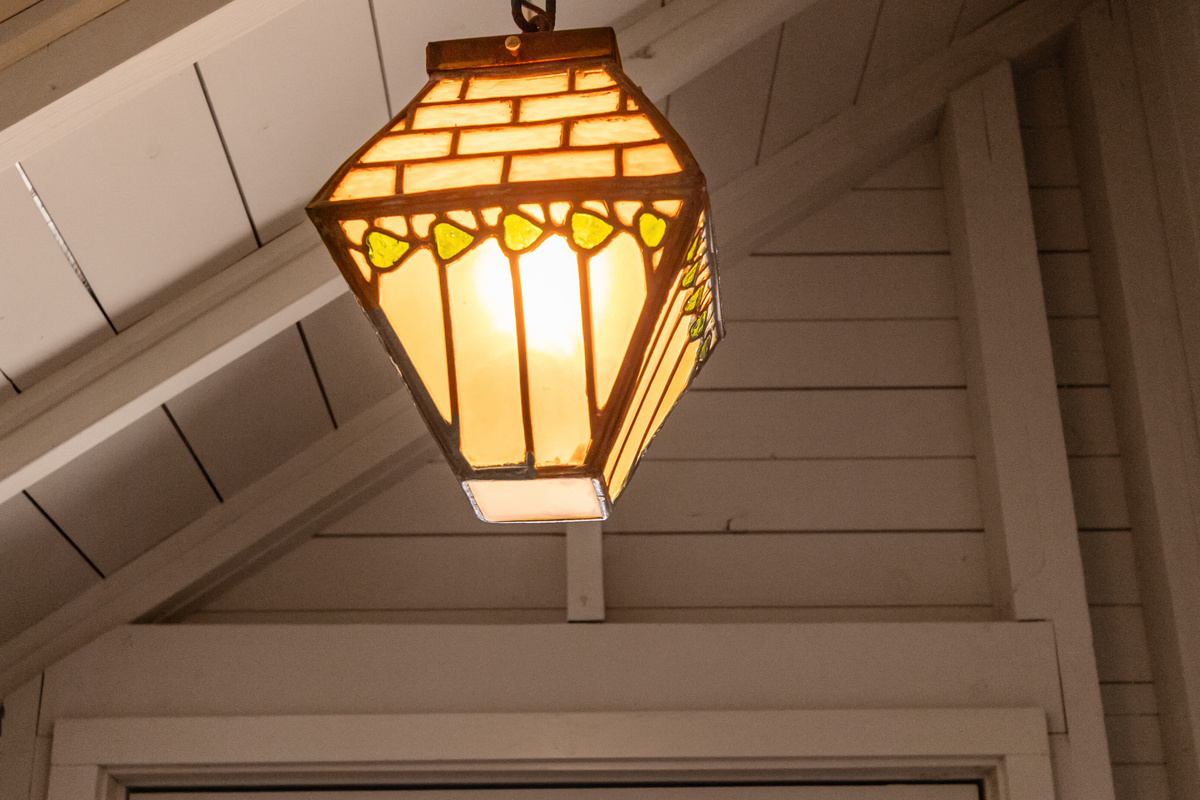 As you head upstairs, charming details like this beautiful stained-glass light add to the warm cottage character found throughout the home.