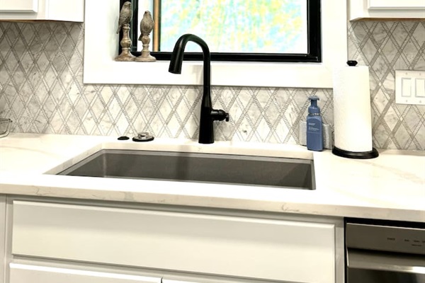 Large sink, garbage disposal, dishwasher, and more. Window peaks into the screened-in porch over looking the back yard.