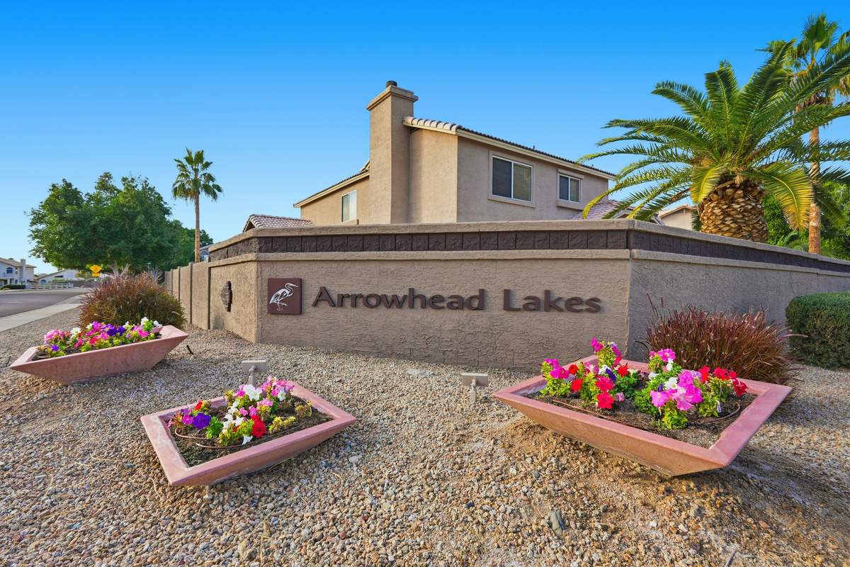 Arrowhead Lakes community entrance with desert landscaping, palm trees, and bright floral curb appeal.