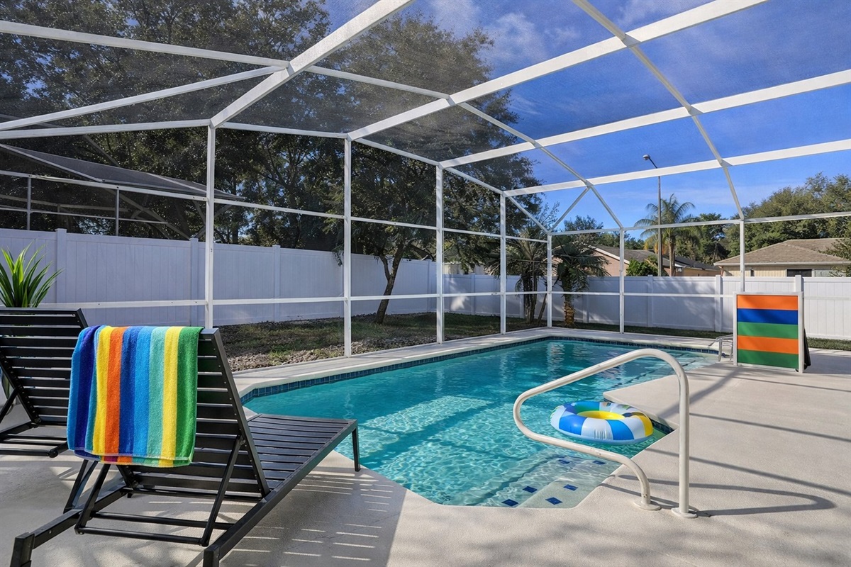 Enjoy a private screened pool area with lounge seating and vibrant accents.