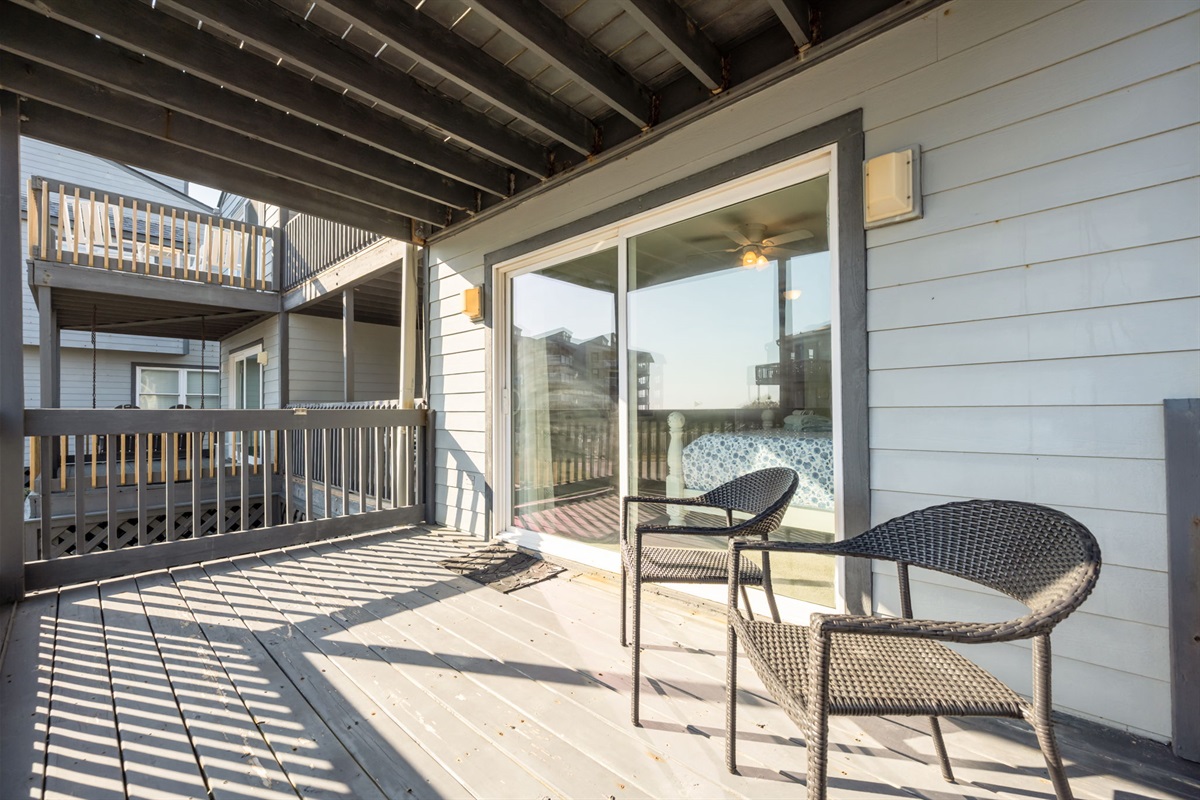 Covered balcony offering shade, seating, and views of the surrounding beach cottages