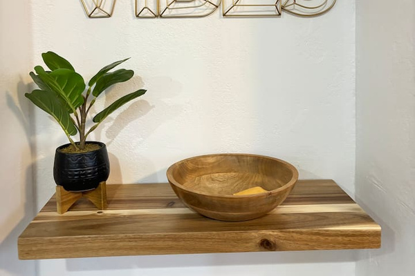 Decorative entry shelf with a small plant, wood bowl, and simple styling that adds a warm arrival touch.