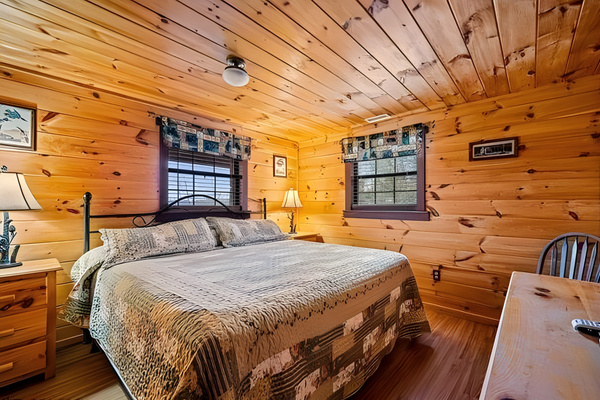 Retreat to this cozy, wood-paneled bedroom offering a comfortable king-size bed, a dedicated desk space, and a classic cabin atmosphere perfect for a restful night's sleep.  Bedroom 1 of 2 on lower level.