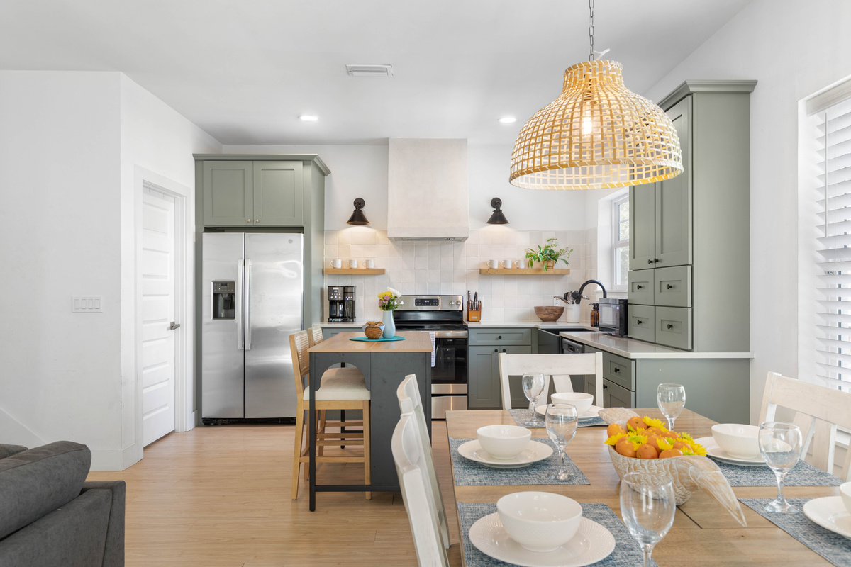 Sage cabinets, a plaster hood, and a coffee maker that will be running before anyone else is up. The island seats two on stools - usually whoever is supervising, or quietly stealing fruit off the counter.