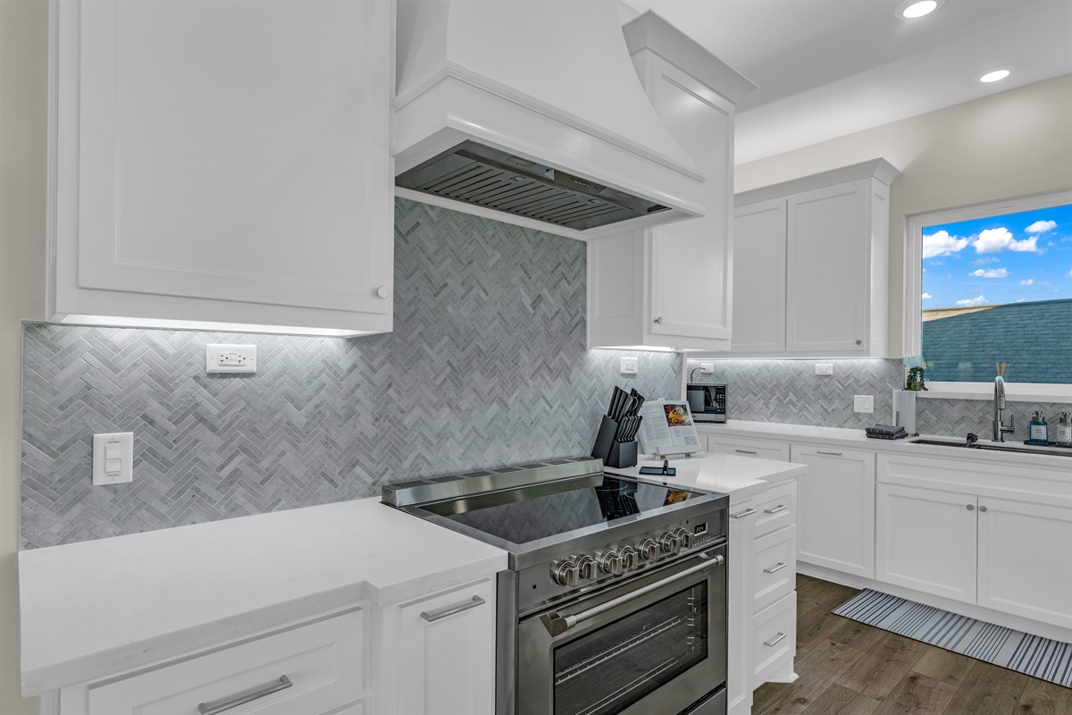 Costa Cristal Kitchen: Sleek kitchen with quartz counters, herringbone backsplash, and a modern stainless-steel range.