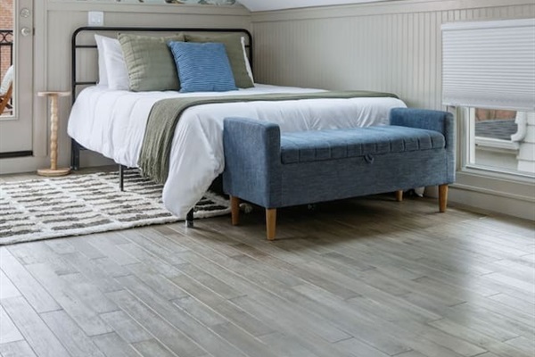 Close-up of one of the queen beds featuring soft linens, accent pillows, and natural light from the skylight above.