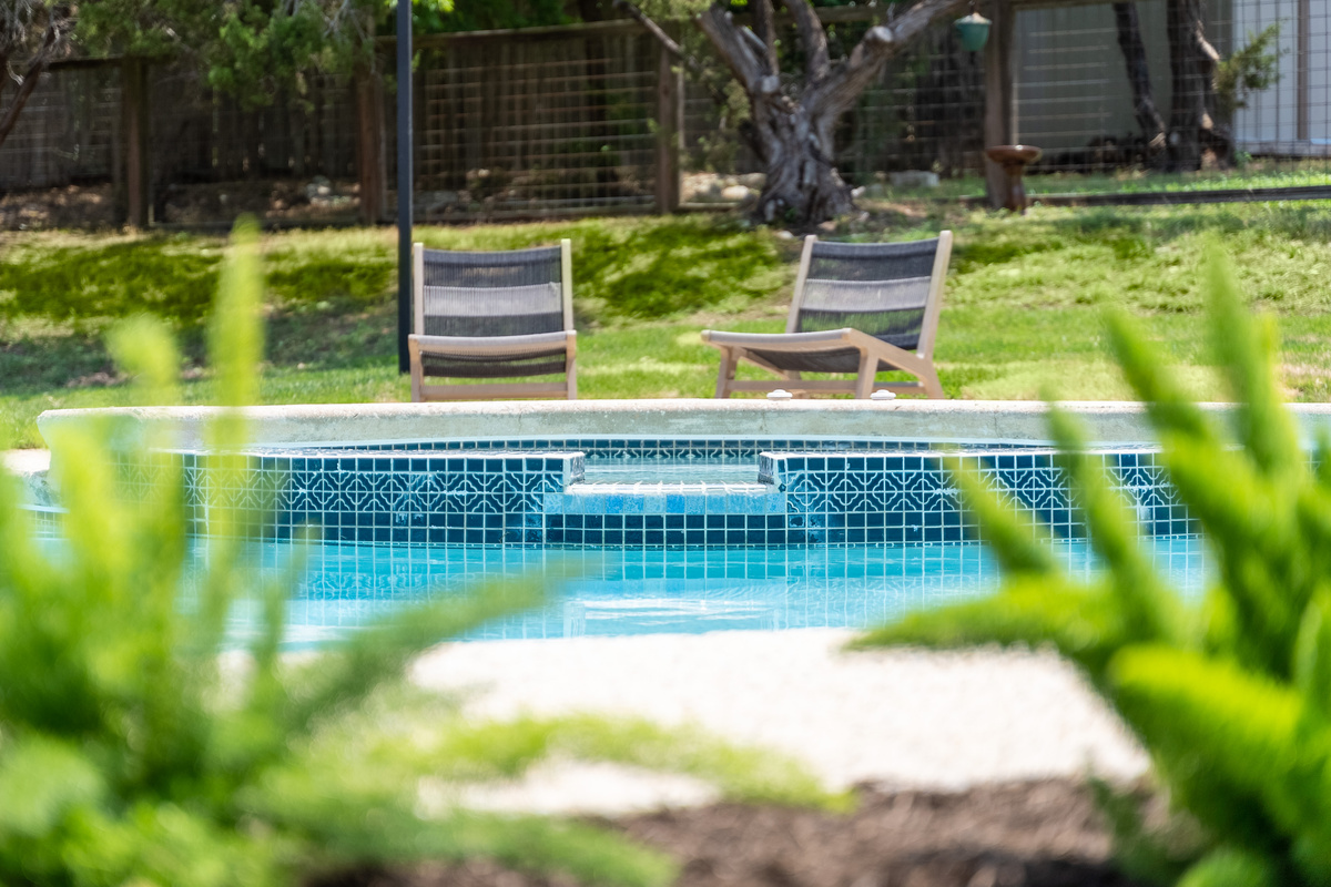 Private hot tub nestled poolside, surrounded by lush greenery.