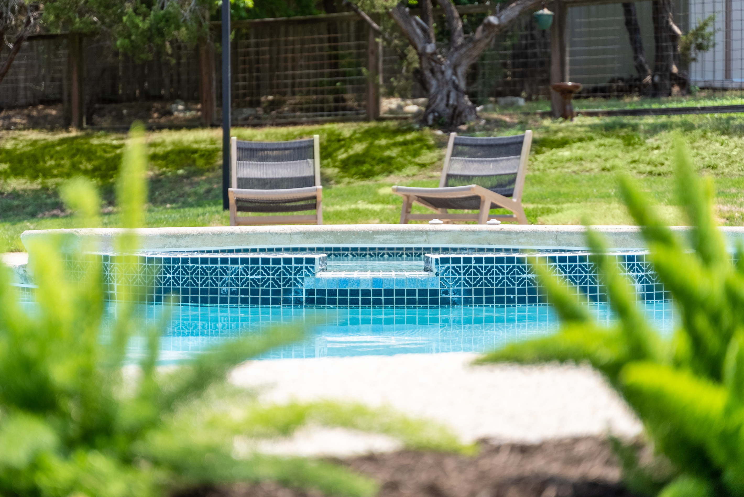 Private hot tub nestled poolside, surrounded by lush greenery.
