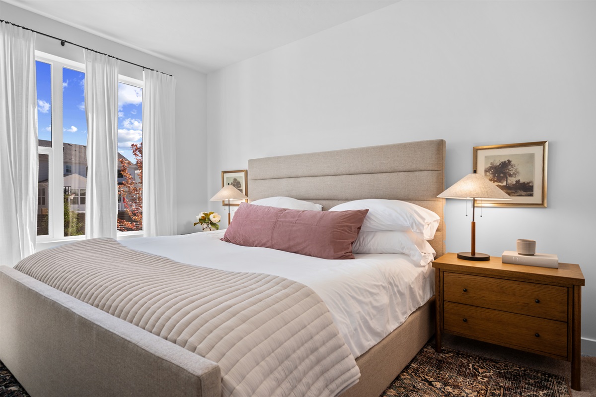 Spacious primary bedroom with a king bed, soft linens, and warm natural light.
