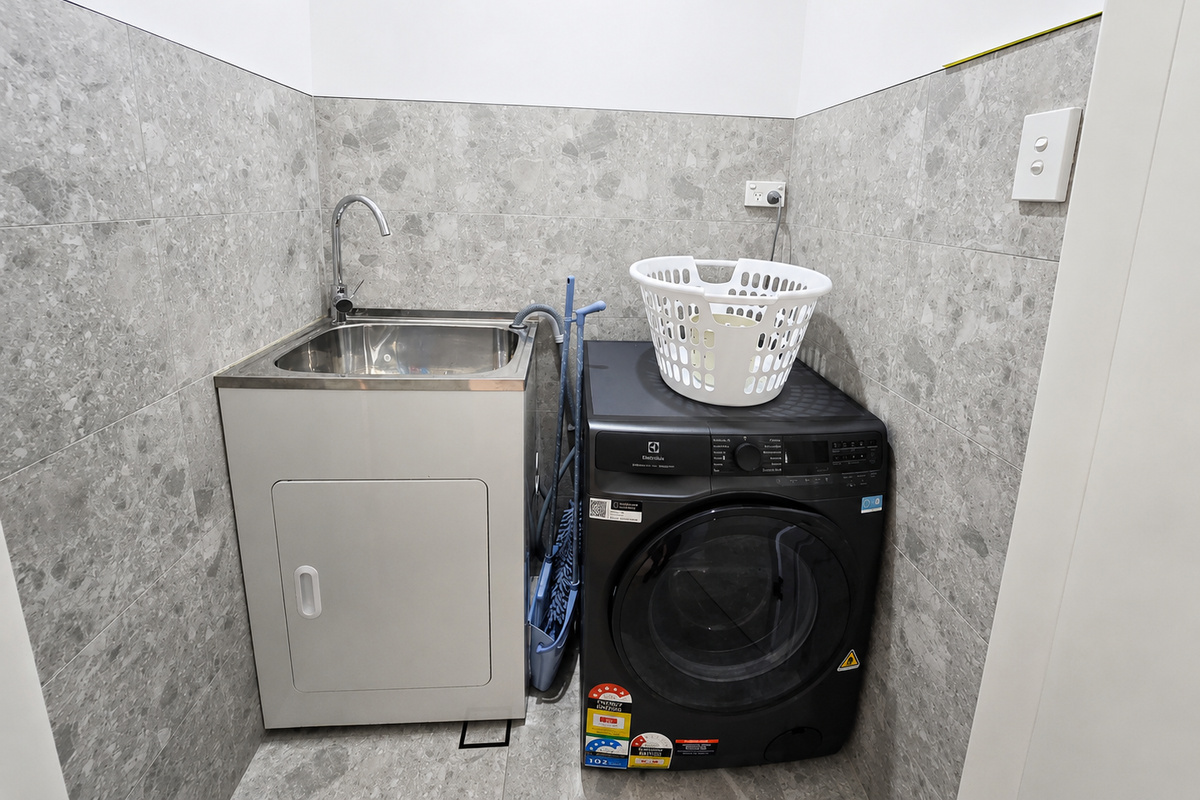 The washer dryer sits directly beside the sink, keeping the laundry setup easy to access and use.