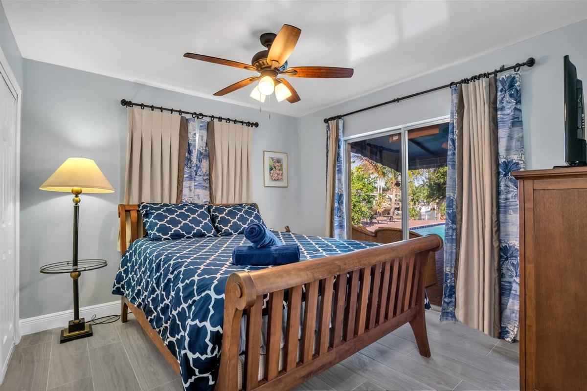 Bedroom#3 with sliding door to the pool, ceiling fan dresser, closet and smart tv.