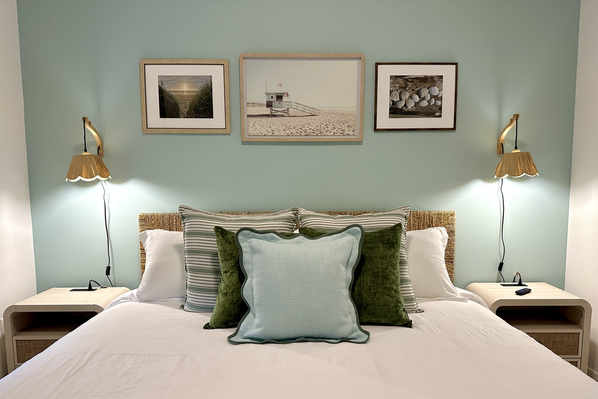 Settle into this quiet king room after a full beach day — soaring ceilings, brass sconces, and coastal art setting the mood no matter what's happening downstairs.