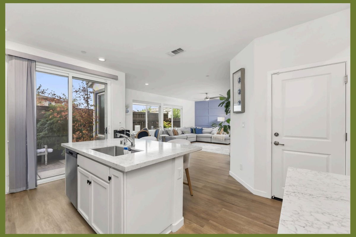 Kitchen island with patio door access, open flow to the living room, and bright natural light throughout the main space.