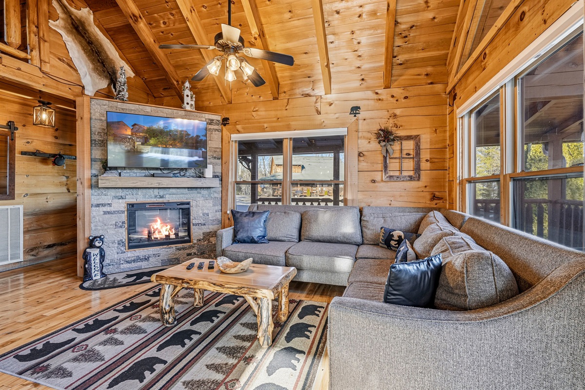 Cozy Smoky Mountain cabin living room with stone fireplace, vaulted wood ceiling & smart TV | Gatlinburg TN log cabin rental with rustic decor & sectional seating for the whole family | The ultimate Great Smoky Mountains vacation retreat near Pigeon Forge