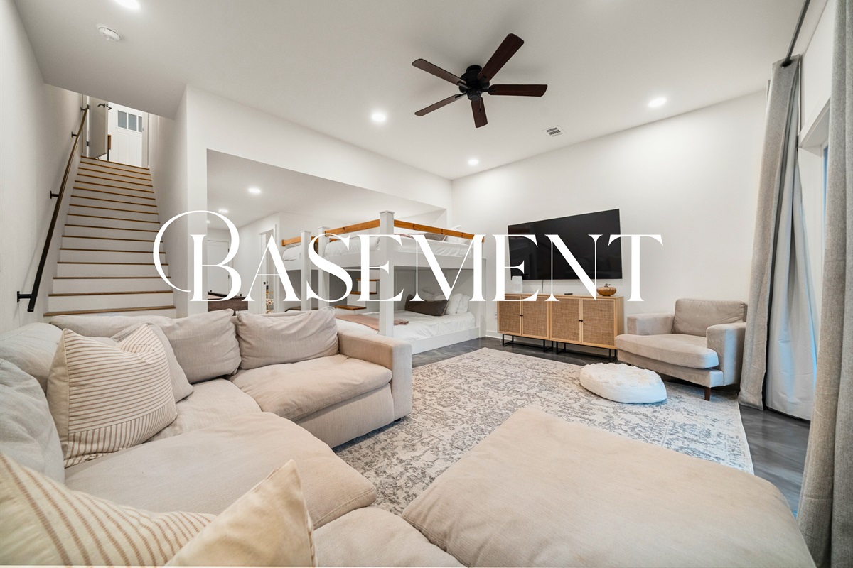 Lower-level family room with large sectional sofa, Smart TV, and game space.