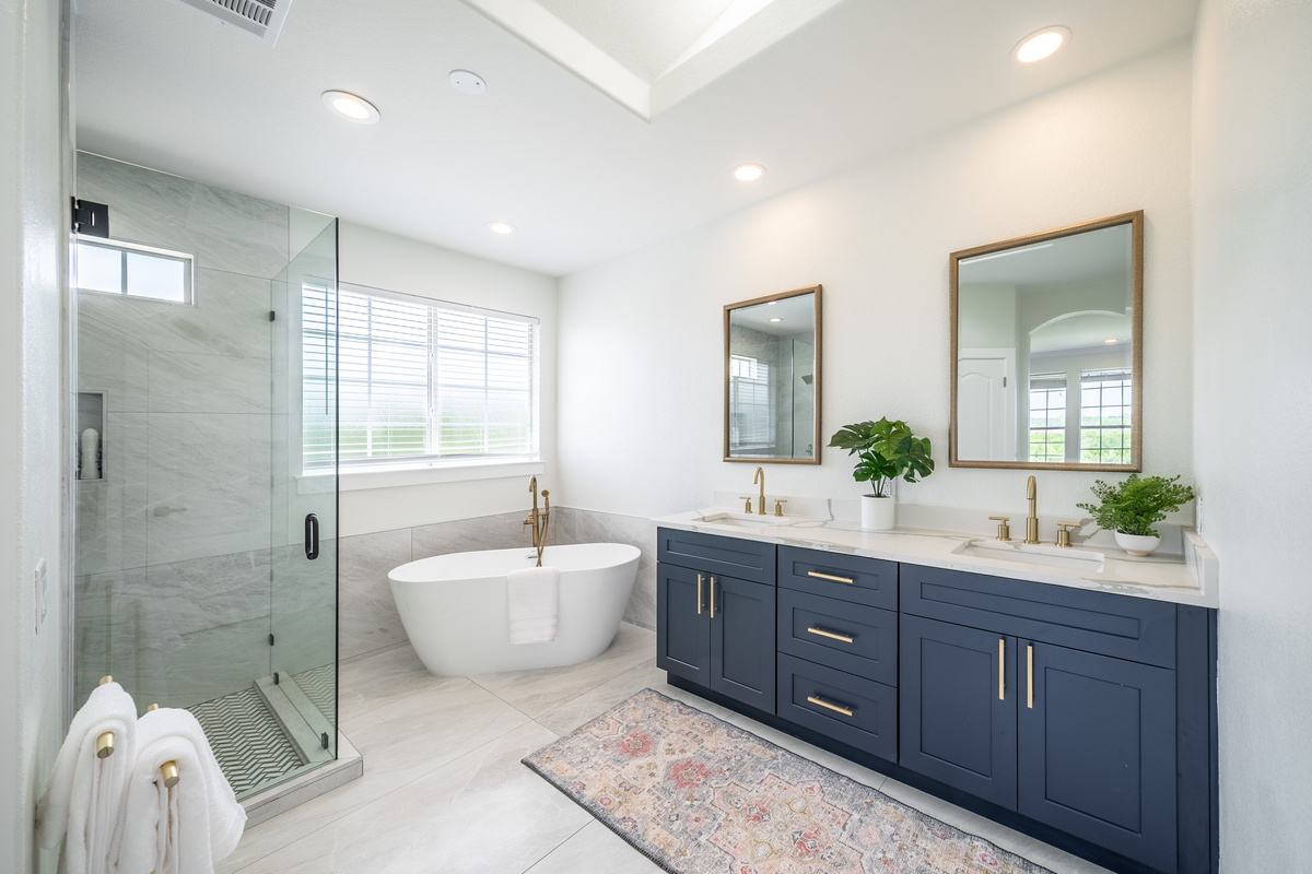 Luxurious primary bath featuring dual vanities, a soaking tub, and a glass walk-in shower.