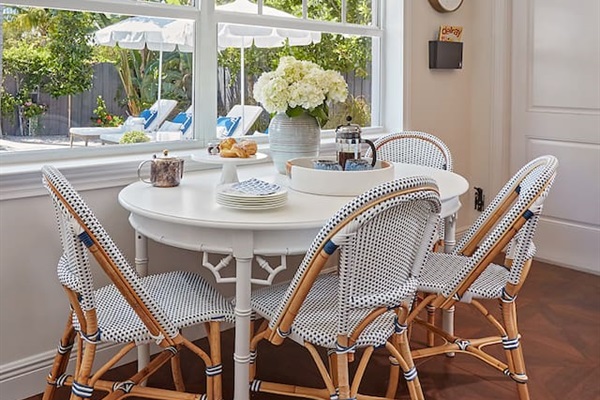 Vintage bamboo dining table surrounded by comfortable Serena & Lily chairs, offering a stylish setting with beautiful views of the pool.