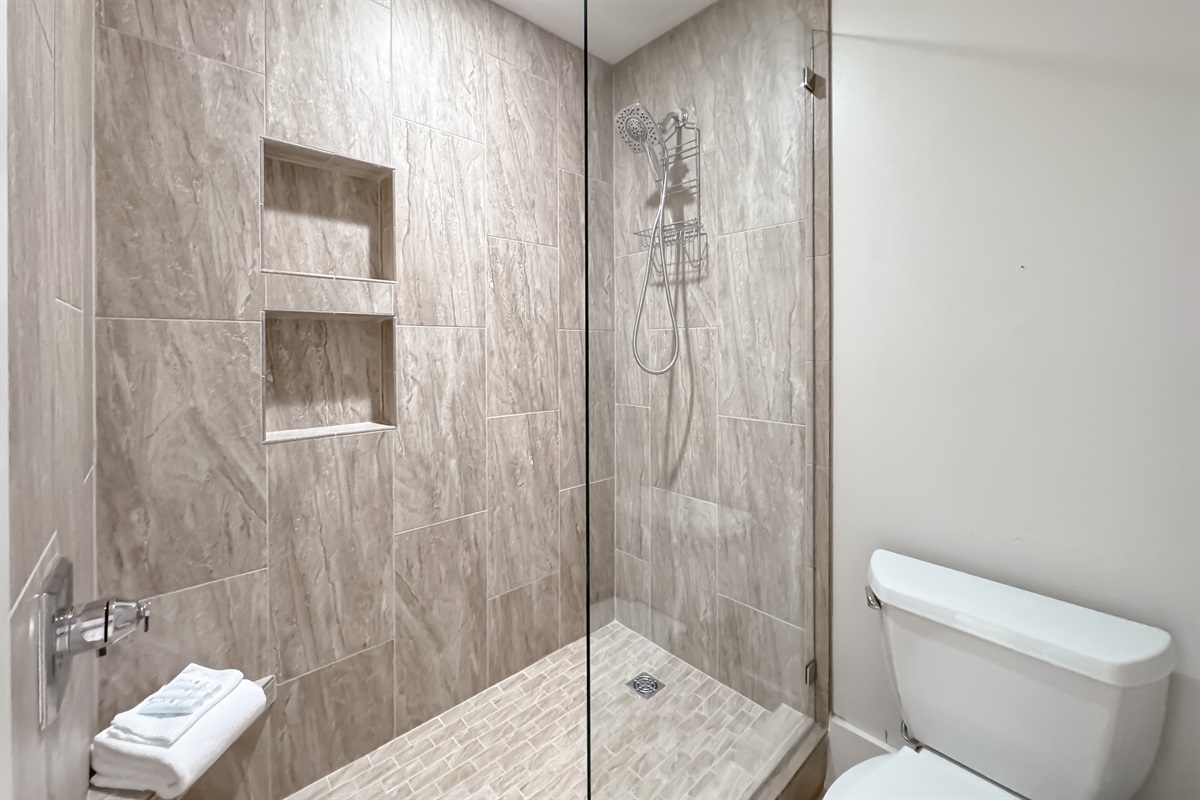 Featuring a sleek glass shower enclosure, a stylish vessel sink, and a large mirror amplifying the space, this bathroom blends functionality with modern aesthetics.