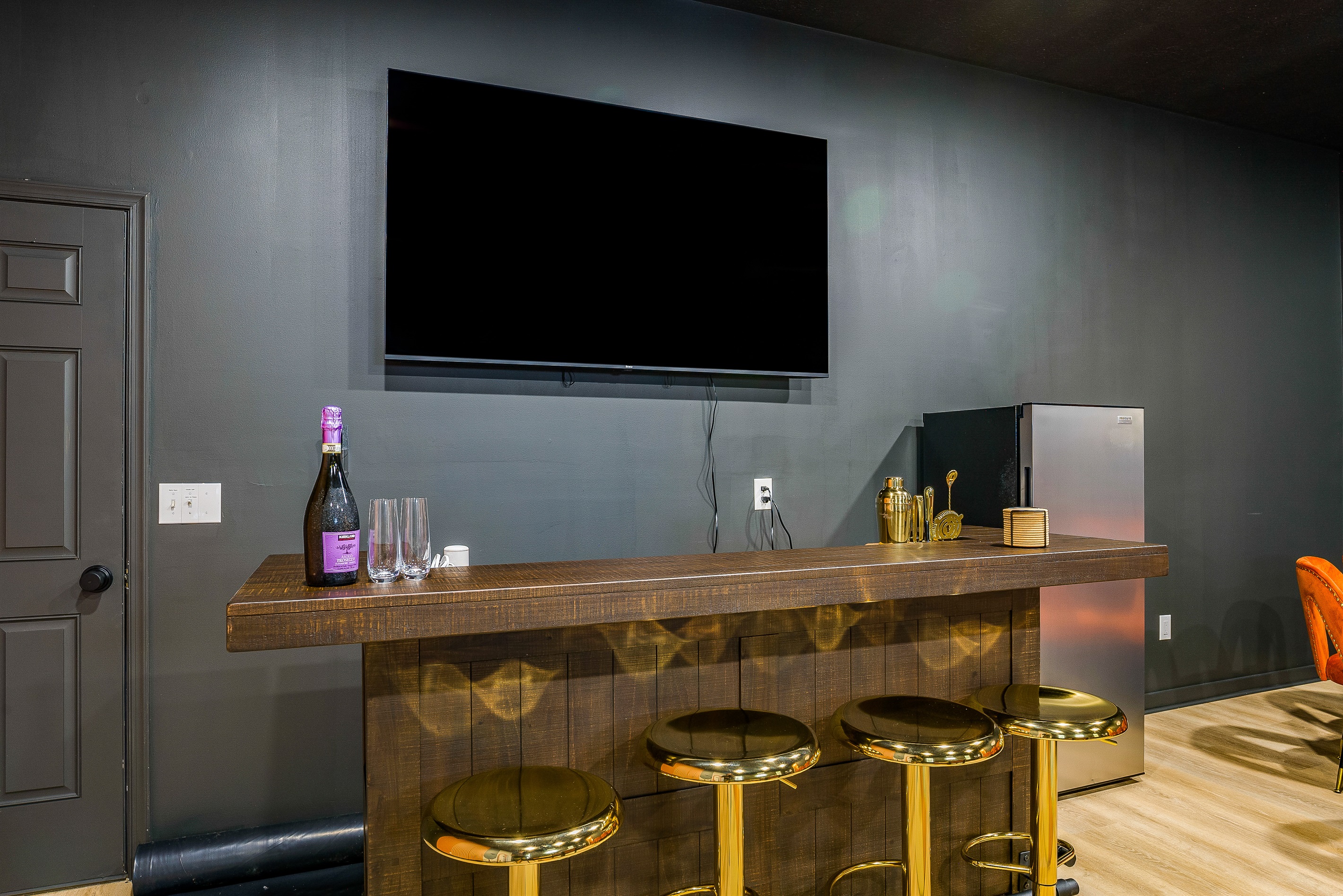 A stylish bar with seating and a big screen — the ideal spot for game-day viewing or evening cocktails
