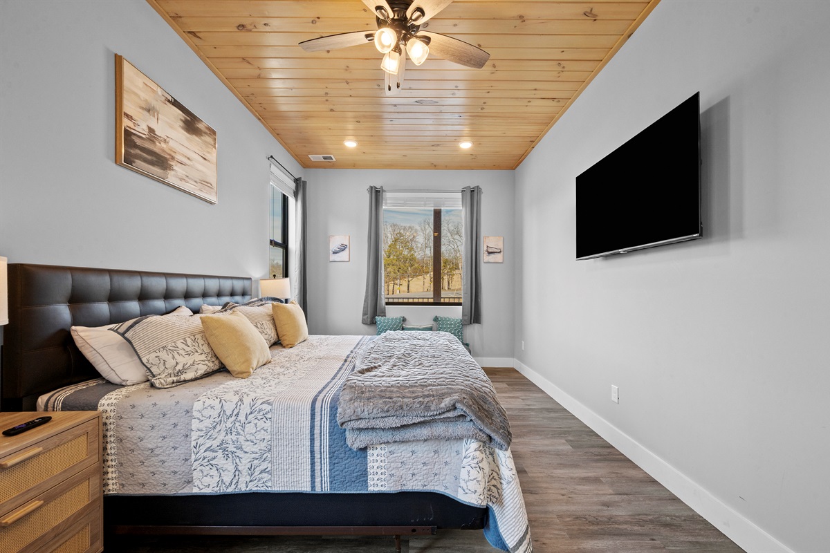 Primary bedroom with wall-mounted TV, nightstands, and soft lighting—designed for rest, relaxation, and a good night’s sleep.