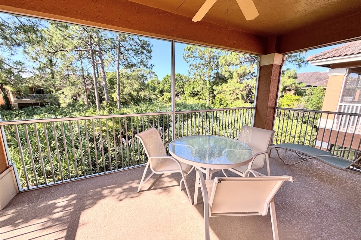 Private screened balcony with outdoor seating and peaceful views of the surrounding greenery.