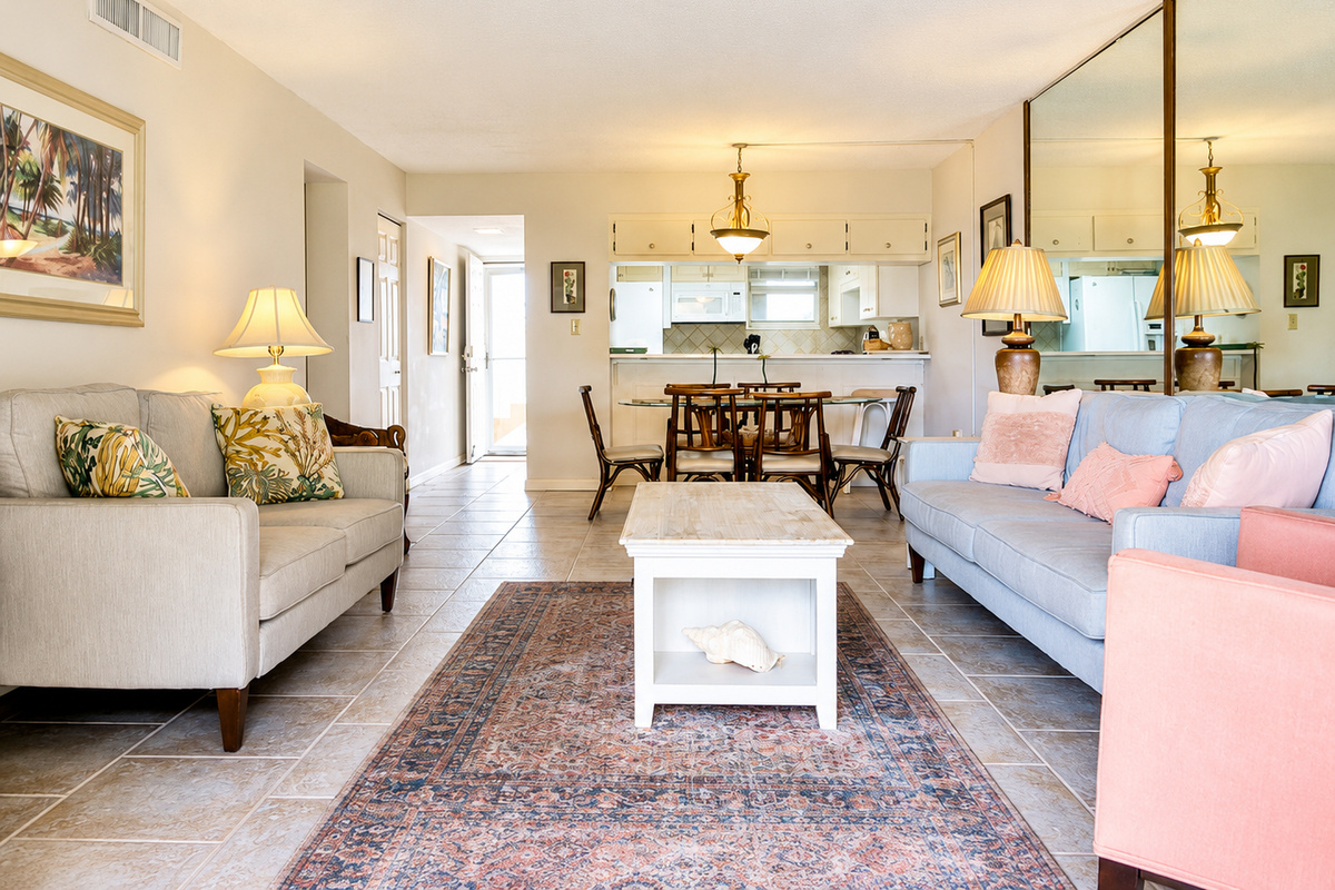 Bright living room with beige and blue sofas, patterned rug, and open kitchen.