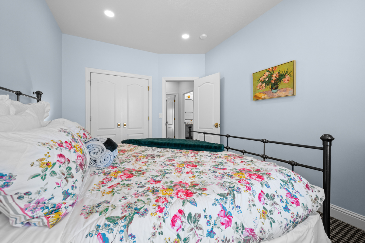 This softly styled bedroom offers a queen-size bed, elegant botanical accents, dresser storage space, and a calm, restful atmosphere.