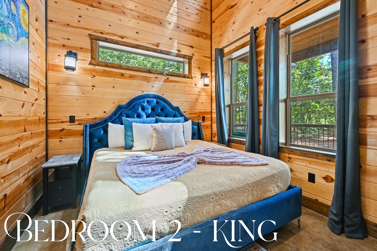Bedroom 2 features a king-size bed, rich wood tones, and a pop of blue for a restful, stylish retreat.