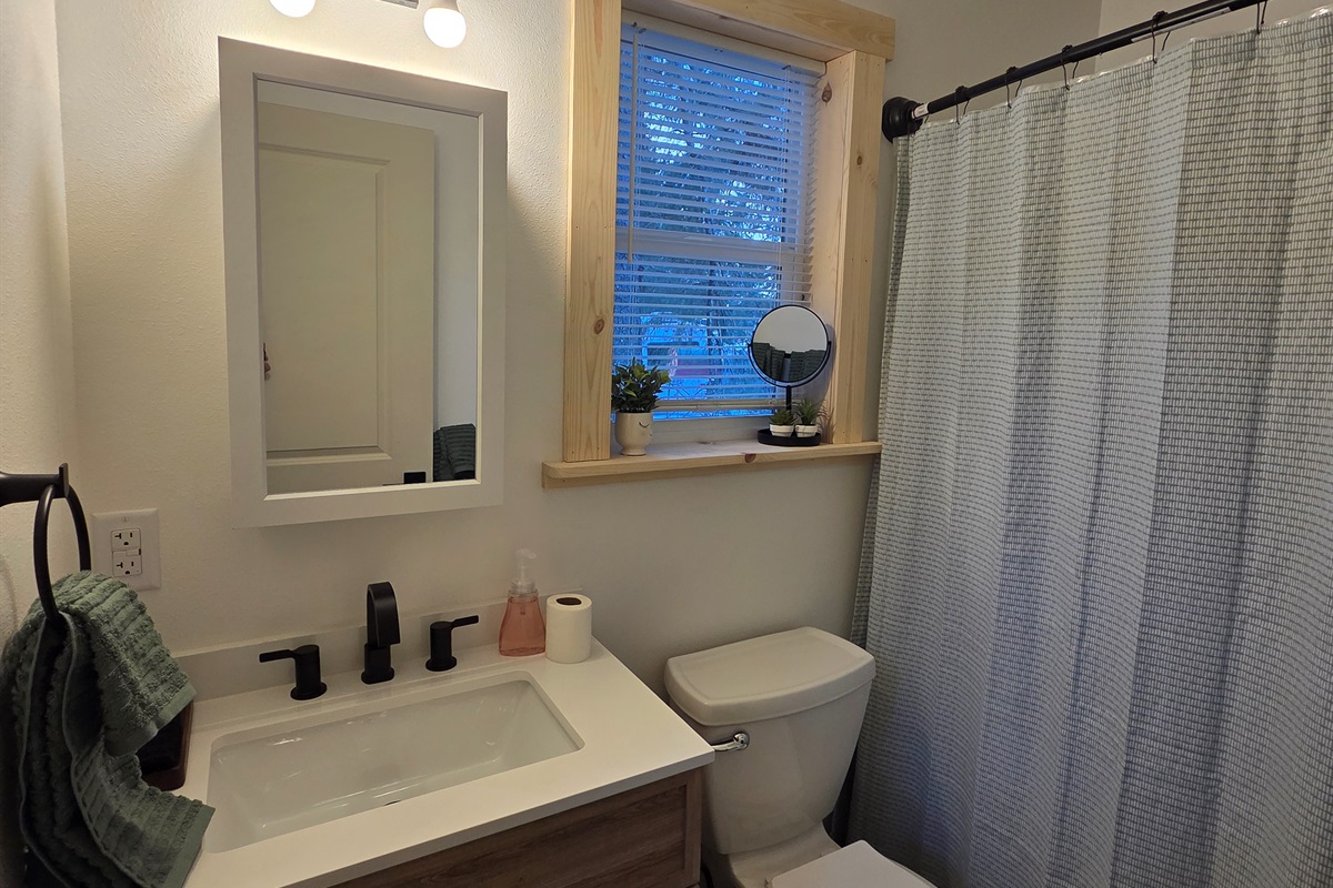 Full bathroom with vanity, toilet and shower/tub combo [Photo is representative but is not from this cabin].