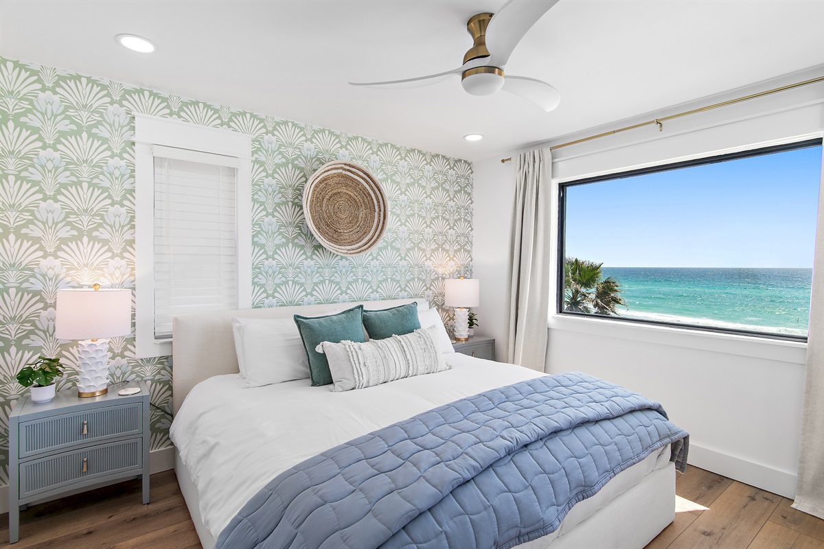 Spacious king suite featuring a smart TV, expansive Gulf-view window, and direct patio access.