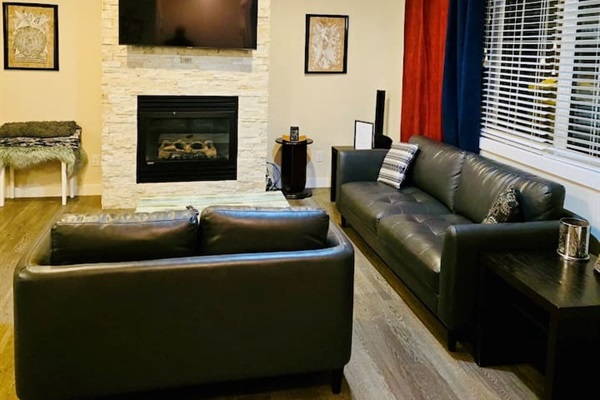 Stylish living room with stone fireplace, leather sofas & smart TV