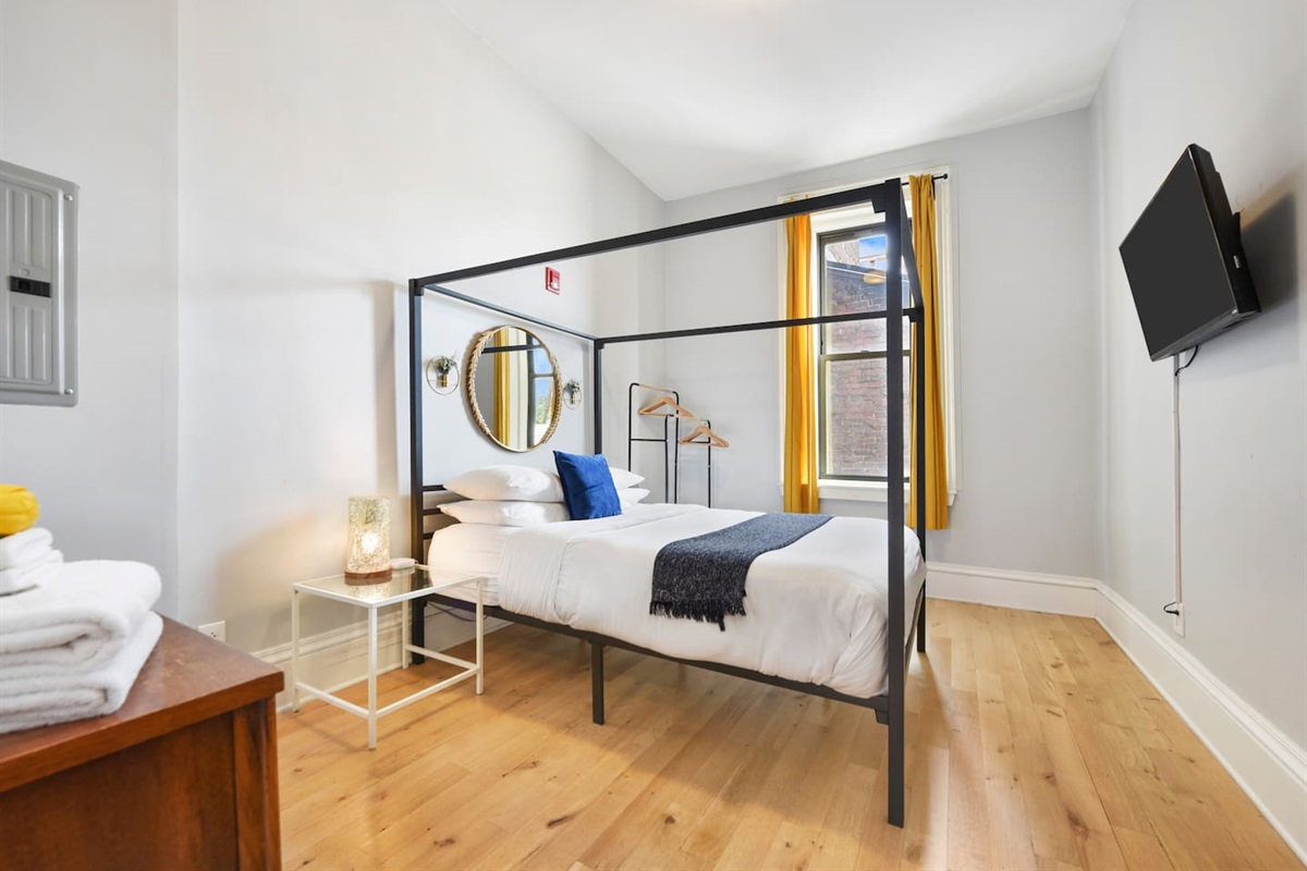 Cozy queen-sized bed with a unique frame and a TV for laid-back movie nights.