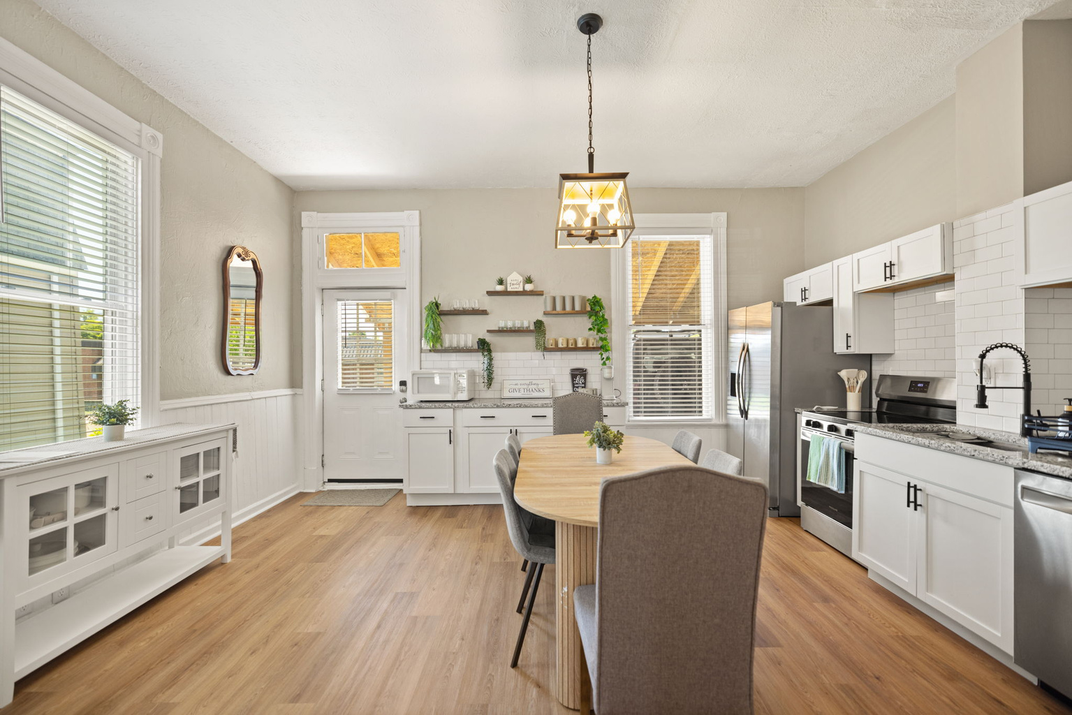 Open-concept kitchen and dining area with pendant lighting, ample cabinetry, and warm wood-tone floors