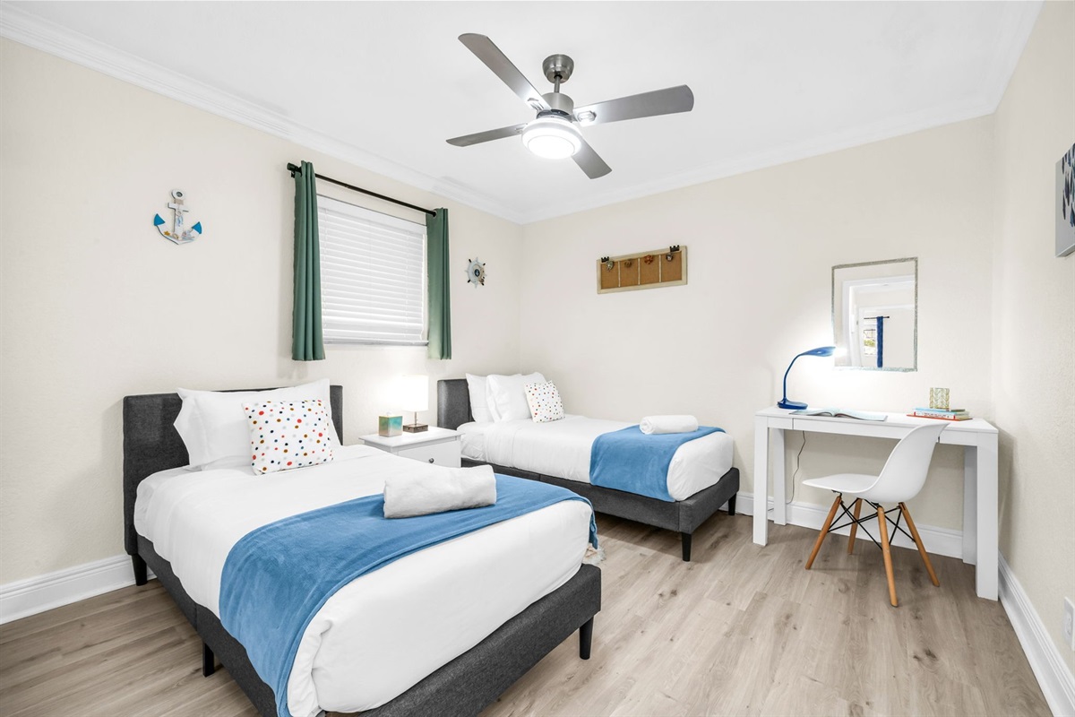 Family-friendly twin bedroom featuring two plush twin beds, coastal décor, and a convenient desk area for work or study.