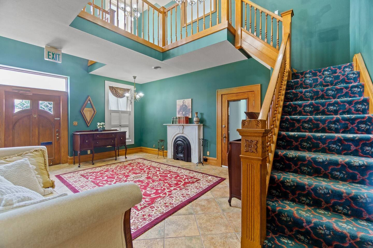 Spacious living area featuring a large red carpet and stairs leading to the second floor, offering a cozy and inviting atmosphere.