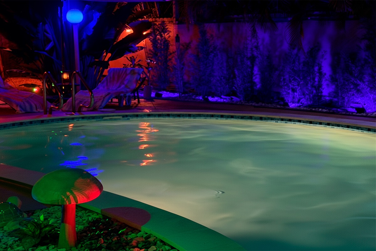 Soft reflections ripple across the heated pool at Garden of Manors, creating a calm, intimate atmosphere enhanced by subtle LED lighting and lush greenery.