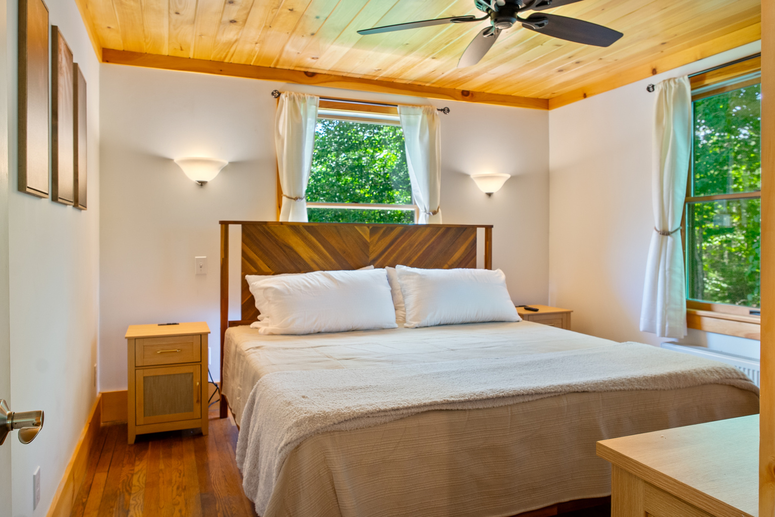 Sleep deeply in the primary bedroom featuring the first of two king-sized memory foam mattresses. Enjoy natural pine ceilings, hardwood floors, and bright window views of the quiet Maine woods, with single-story access on the main floor.